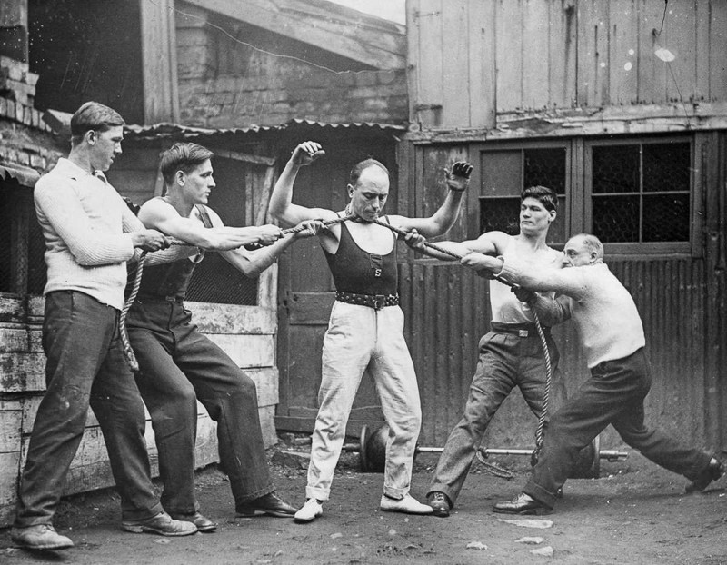 26 февраля 1932 года. Том Джойс, утверждавший, что является сильнейшим человеком в Бристоле, демонстрирует свою силу, когда четверо мужчин тянут веревку, обмотанную вокруг его шеи. история, люди, сила