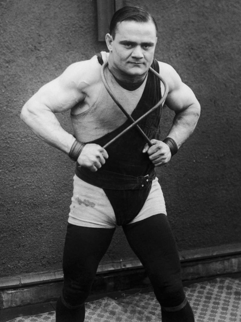 1925 год. Греческий боксер и силач Джаст Лессис демонстрирует свое мастерство, сгибая железный прут вокруг шеи. история, люди, сила